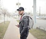 A fashionable young man in Budapest checking his smartphone on a busy street.